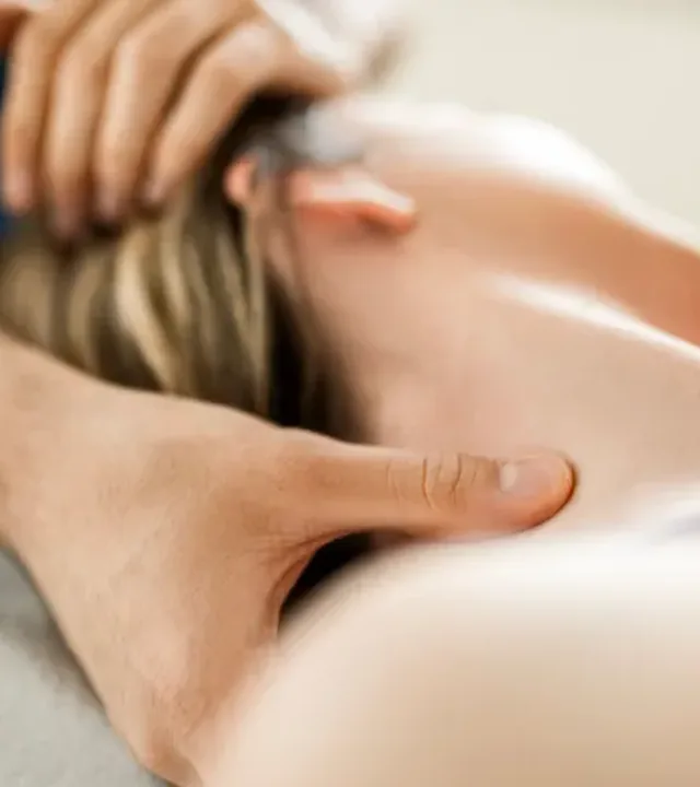Clinician's hands supporting a patient's head and neck during manual therapy